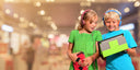 Two children using handheld gaming devices in a cozy indoor space, highlighting educational tech engagement with NutKase branding