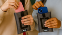 Two girls placing their iPhones into the NutKase Student phone pouch, demonstrating everyday school use