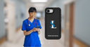 Nurse in blue scrubs using a smartphone with a black phone case featuring a logo in a hospital setting.
