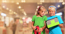 Two children wearing headphones using tablets with protective cases and headphones