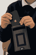 Student placing a black iPhone with visible Apple logo into a NutKase phone pouch 